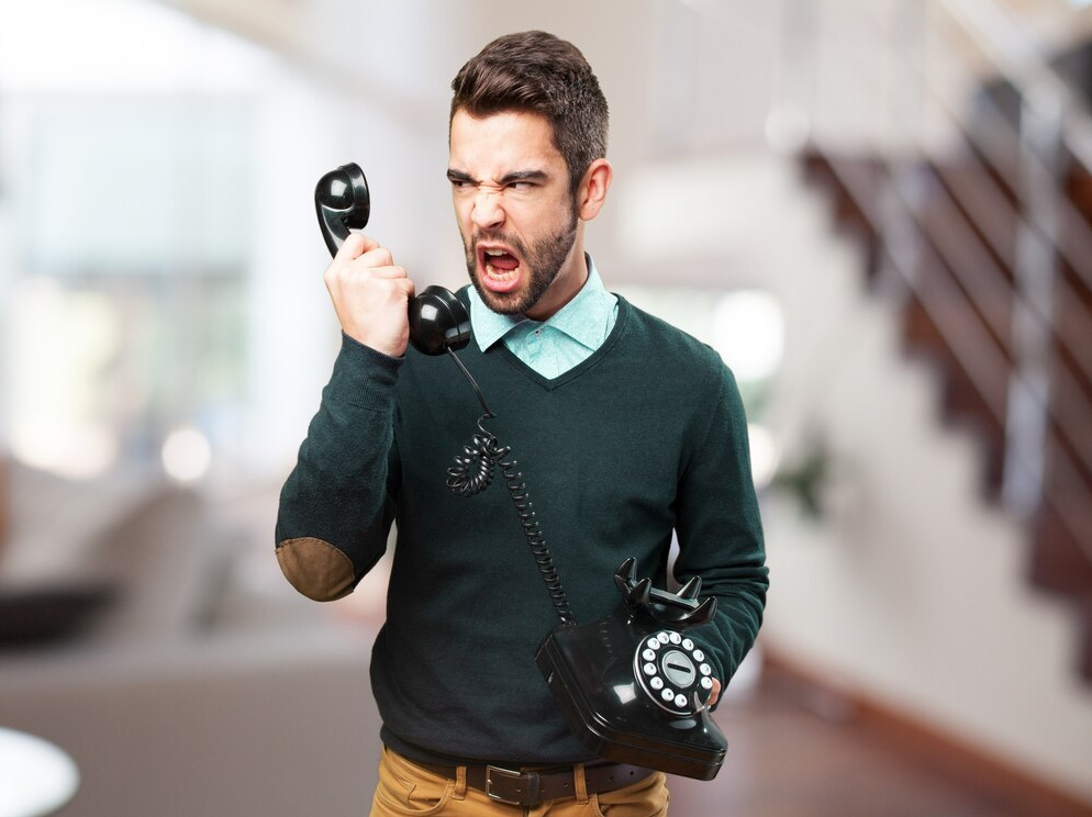 Furious man yelling at an old phone cold calling