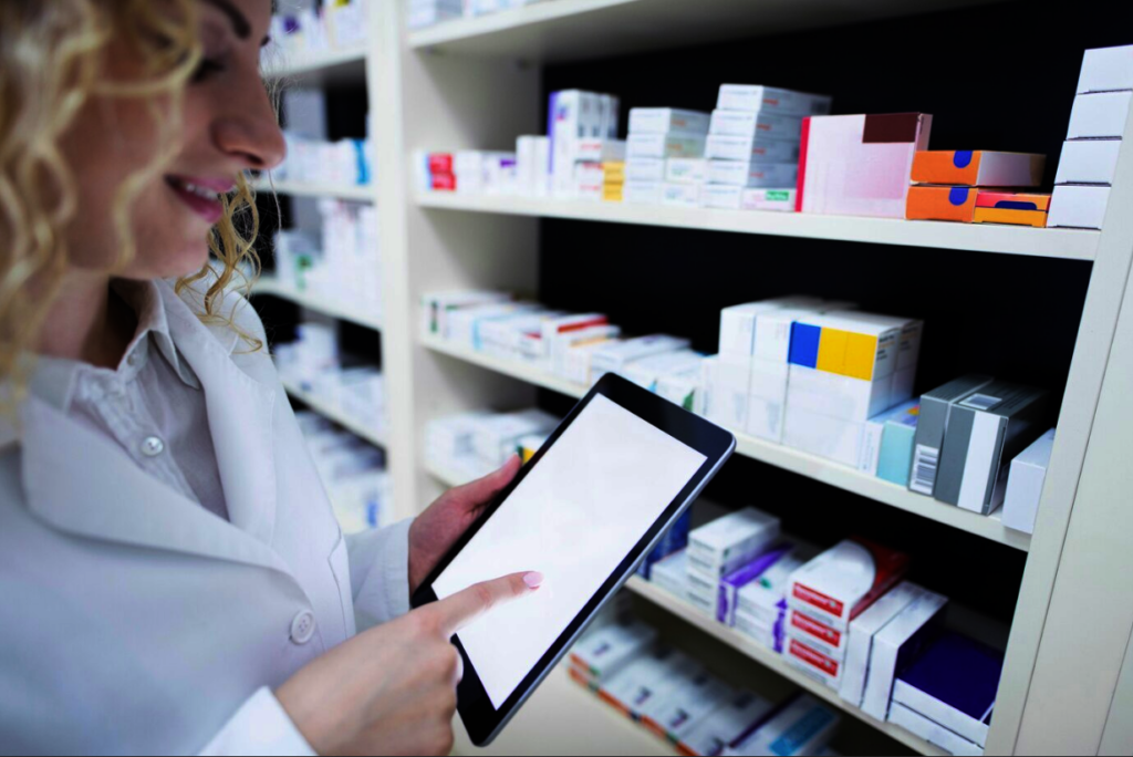 Pharmacist holding tablet by the shelf full of medicine in drug store and checking medication availability and specification. Dokumentenmanagements
