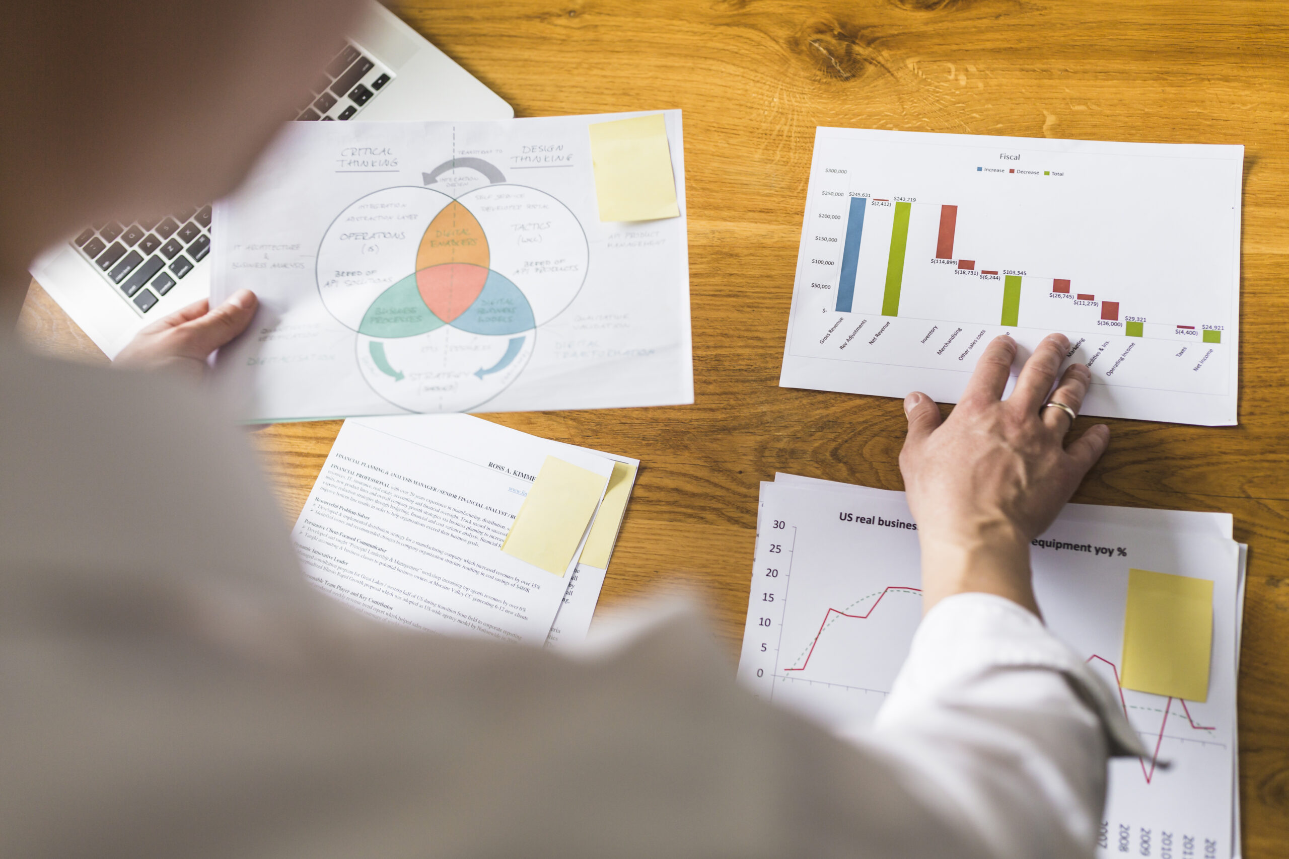 businessperson-s-hand-analyzing-graph-wooden-desk