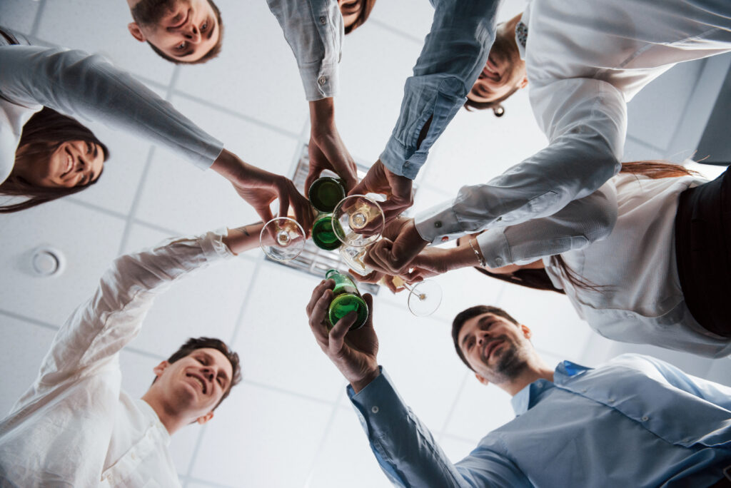 Photo from below. Knocking glasses in the office. Celebrating success founder-led sales