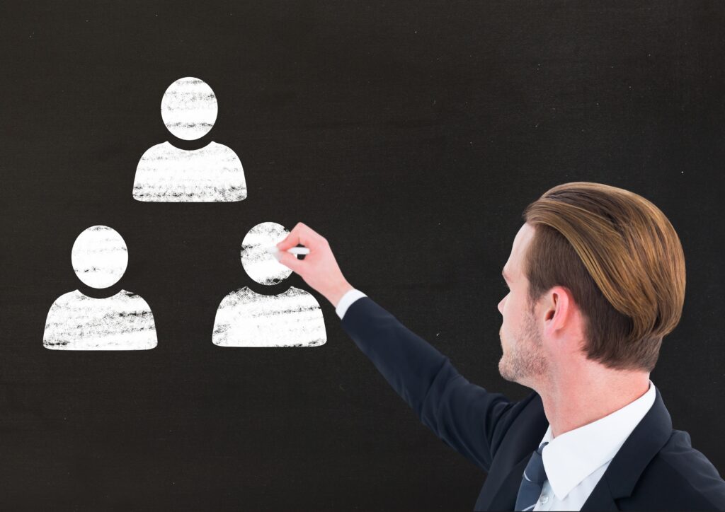 Businessman drawing user icons with chalk on blackboard